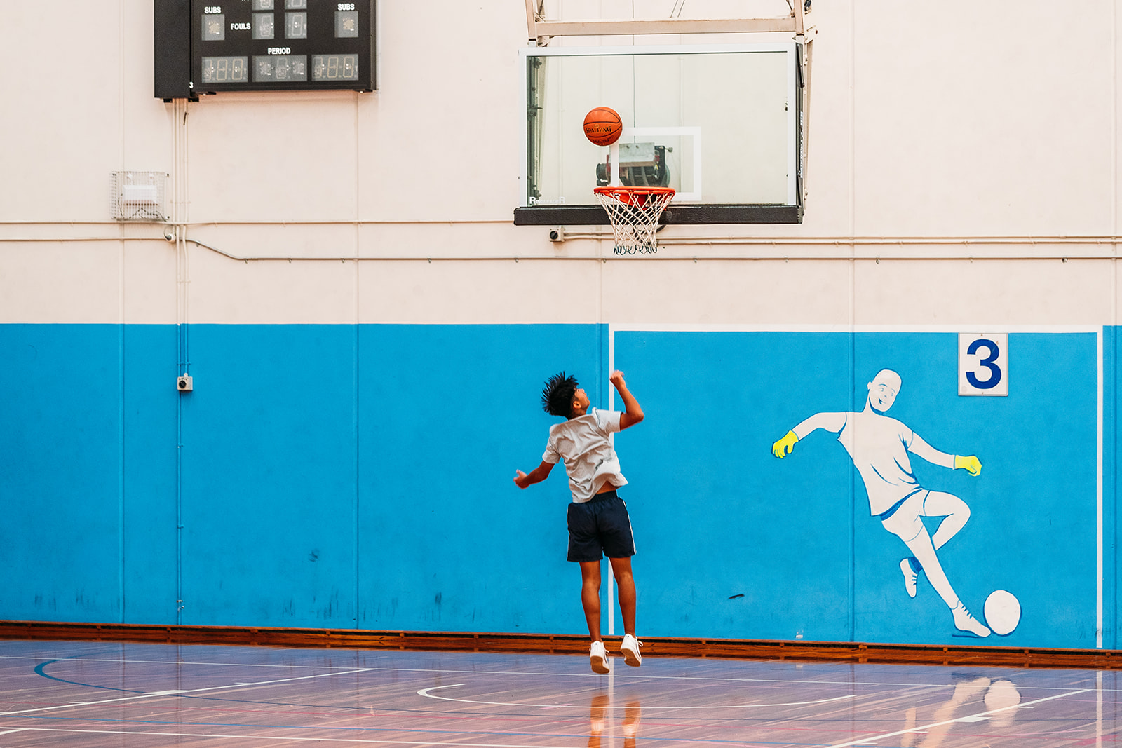 Teenager shooting basketball hoops at Menai Indoor Sports Centre